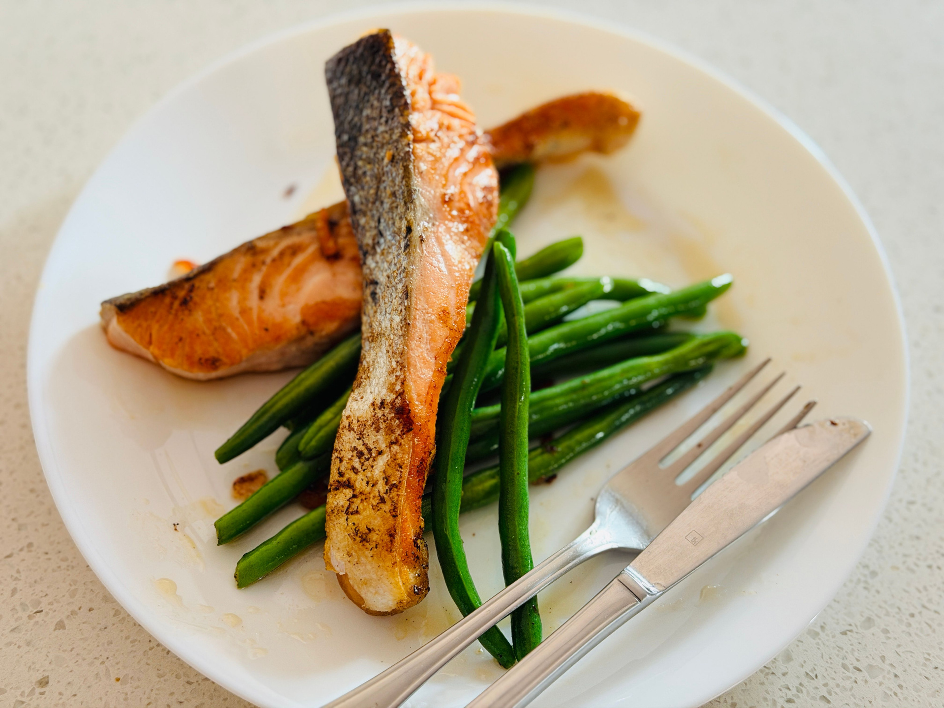 Seared salmon fillets with crisp green beans on a white plate
